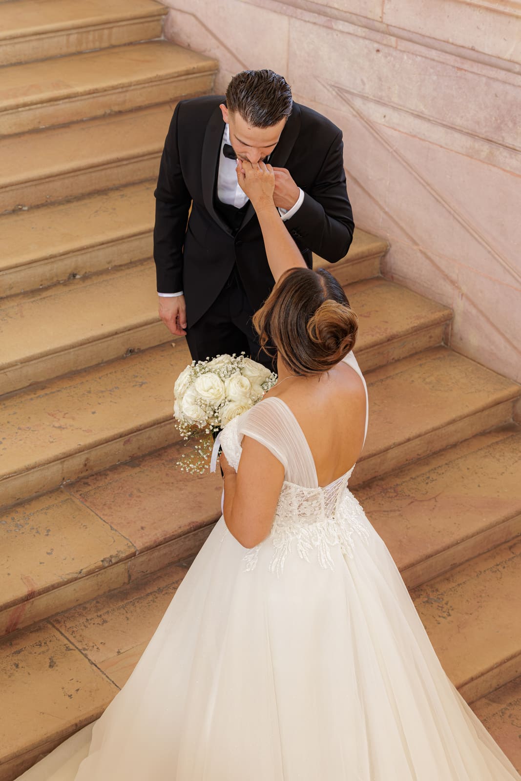 Le marié baise la main de la mariée dans l'escalier